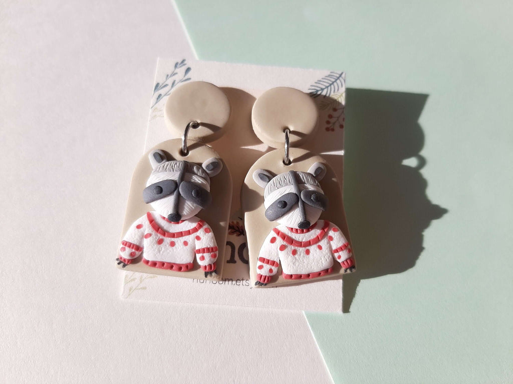 funny raccoon earrings in a white sweater